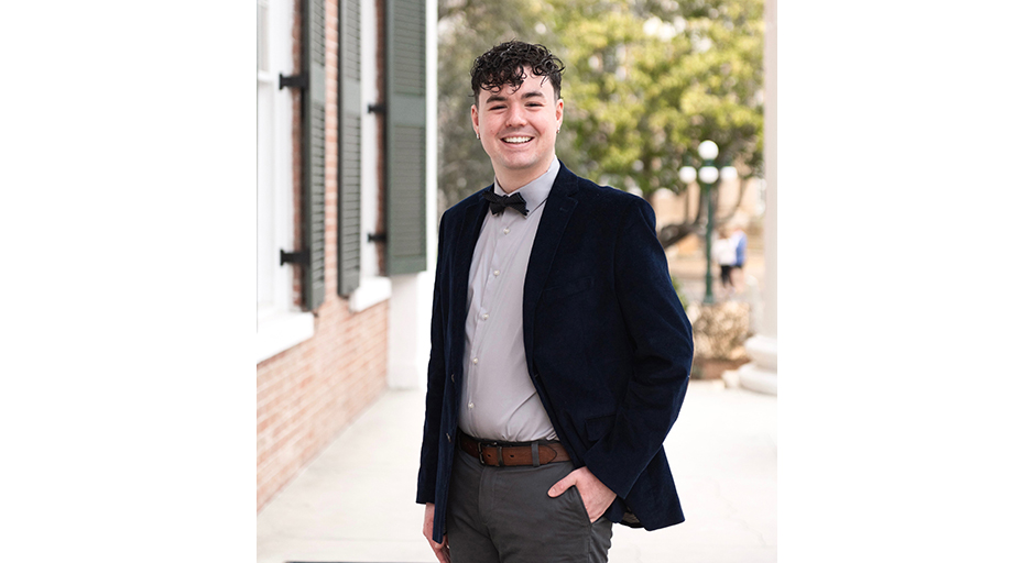 Outdoor portrait of a young man wearing a black coat and a bowtie.